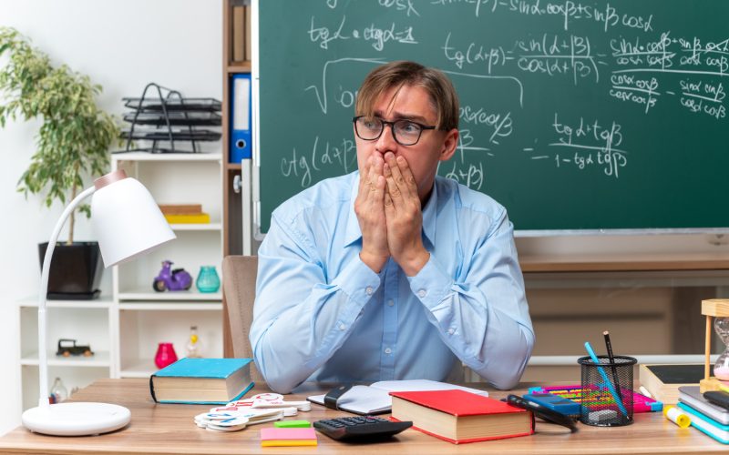 Professor sentado na sala de aula pensando em como lidar com o mau comportamento dos alunos