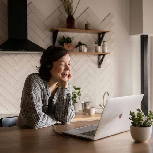 Uma mulher eficiente gerenciando sua equipe de forma remota a partir da cozinha, utilizando ferramentas online para otimizar a comunicação e a colaboração.
